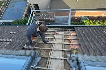 Man repareert dakplaten op een huisdak.